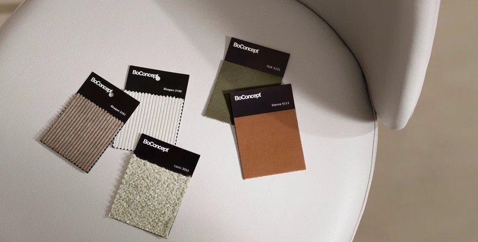 Échantillons de tissu BoConcept sur une chaise blanche, présentant diverses textures et couleurs.